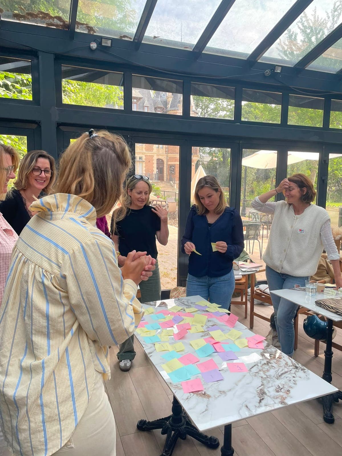 Groupe debout autour d'une table couverte de post-its colorés pendant un atelier collectif
